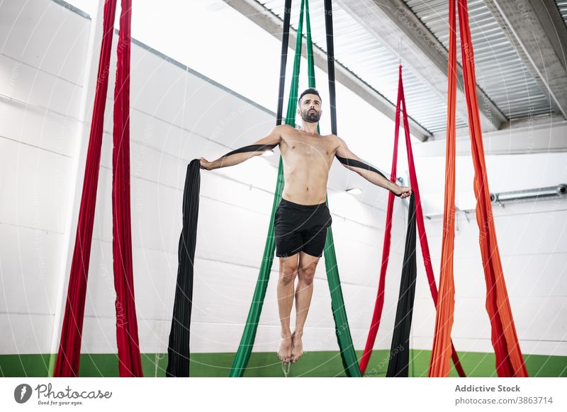 Bärtige Tänzerin balanciert auf Luftseiden Mann Tanzen Antenne Seide Gleichgewicht Atelier Probe gymnastisch akrobatisch hängen männlich ohne Hemd Bändchen