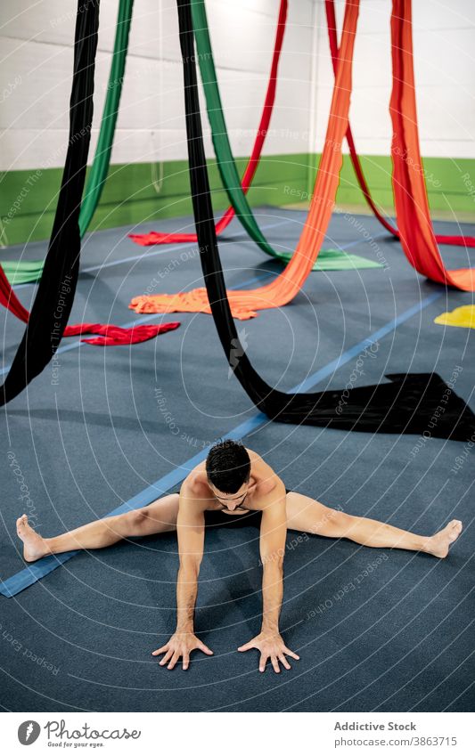 Männlicher Tänzer streckt sich in der Nähe von Luftseiden Mann Dehnung Stock Seide Antenne Atelier beweglich gymnastisch vorbereiten Probe männlich Bändchen