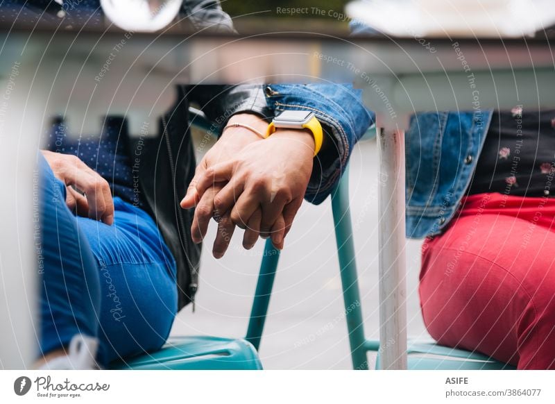 Lesbisches Paar hält Hände unter dem Tisch lesbisch lgbtq schwul mittleres Alter 40 50 Beteiligung Händchenhalten Mittelteil versteckend Homosexualität Frauen