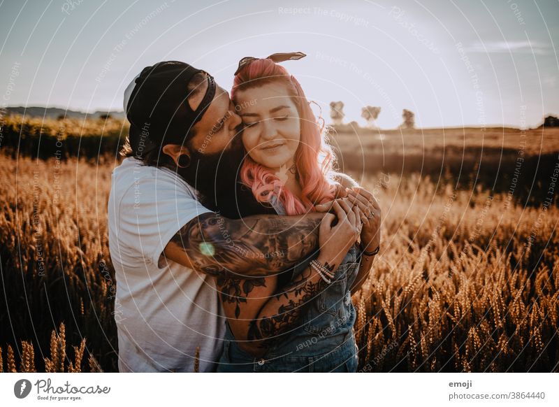 Paar mit Tattoos und pinken Haaren küssen sich Frau Mann Hipster trendy kuscheln innig pinke haare kornfeld Draussen paar liebe verliebt umarmung