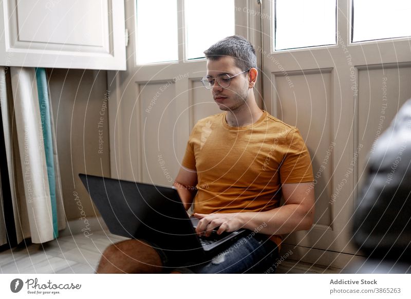 Beschäftigter Mann arbeitet am Laptop im Wohnzimmer freiberuflich abgelegen Arbeit heimwärts Tippen Projekt Konzentration Browsen männlich lässig Outfit Stock
