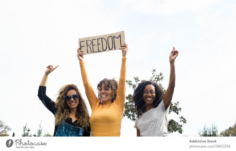 Diverse Frauen mit Plakat Freiheit im Park Konzept Aufschrift Freund Zusammensein plakatieren Einheit sich[Akk] sammeln multiethnisch rassenübergreifend