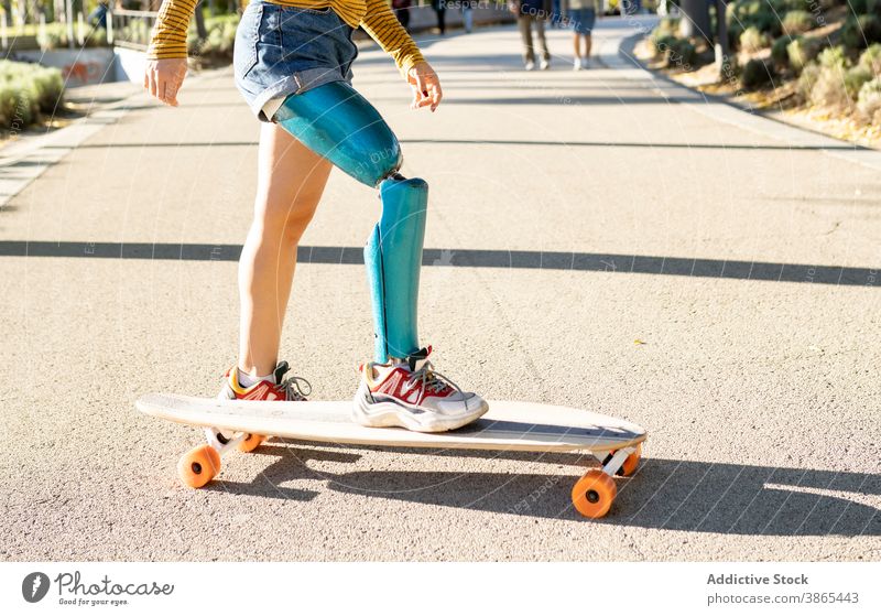 Crop Frau Reiten Longboard in der Stadt Bionik Prothesen Mitfahrgelegenheit Skater Bein heiter deaktivieren künstliches Glied Amputierte Straße urban Optimist