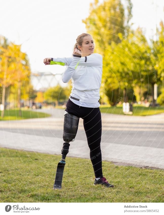 Sportlerin mit Beinprothese beim Aufwärmen im Park Läufer Prothesen paralympisch Frau Training Vorwärtsbeuge Übung künstliches Glied Amputation Bionik