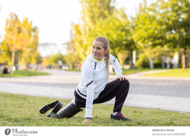 Sportlerin mit Beinprothese beim Aufwärmen im Park Läufer Prothesen paralympisch Frau Training Vorwärtsbeuge Übung künstliches Glied Amputation Bionik