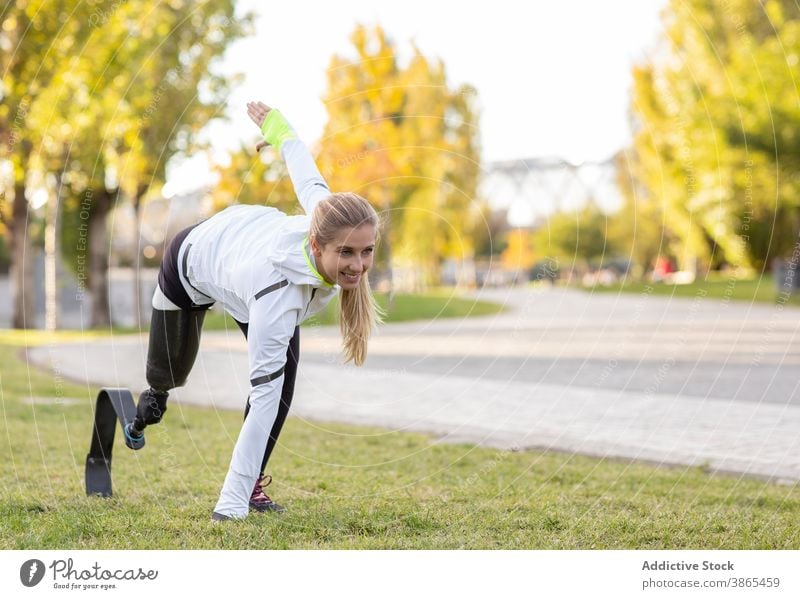 Sportliche Frau mit Beinprothese beim Training im Park explosiv Start Läufer paralympisch Prothesen laufen Sportlerin künstliches Glied Übung Bionik bereit
