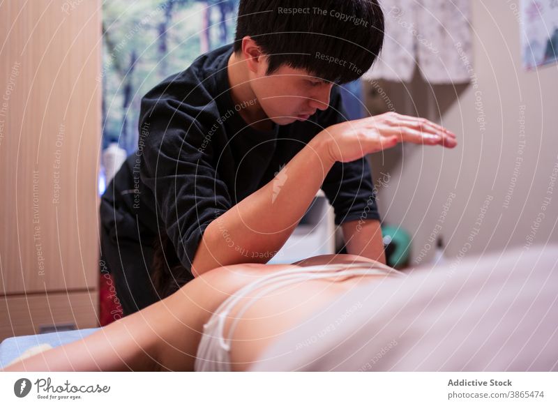 Masseur, der den Klienten während der Rehabilitationsmassage in einem professionellen Salon anlegt Massage geduldig setzen Leckerbissen Pflege Therapie