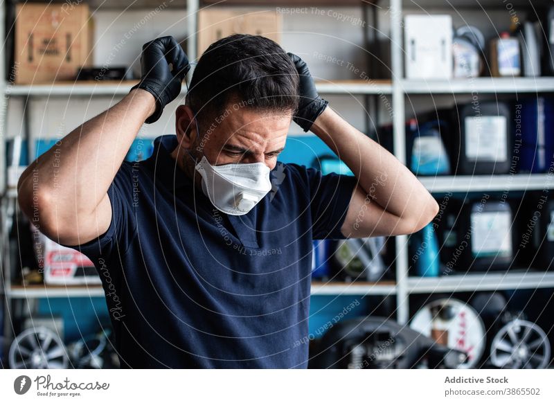 Arbeiter setzen weiße Gesichtsmaske Mann Mundschutz angezogen Handschuh Garage vorbereiten Latex Uniform beschäftigt männlich Personal Job Mitarbeiter