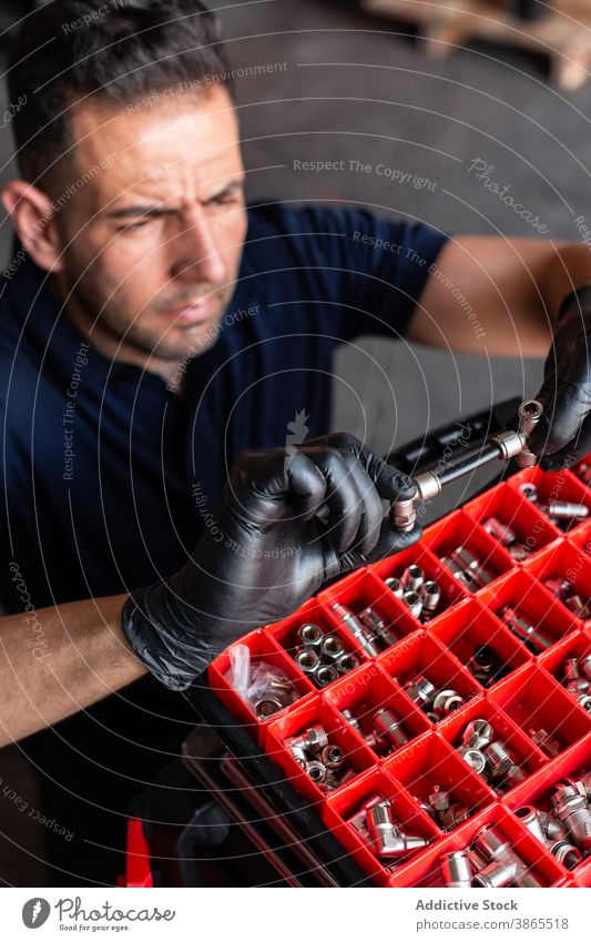 Männlicher Techniker prüft Werkzeug in der Werkstatt Mann Mechaniker untersuchen Kasten Garage Arbeit Handschuh modern professionell männlich Erwachsener