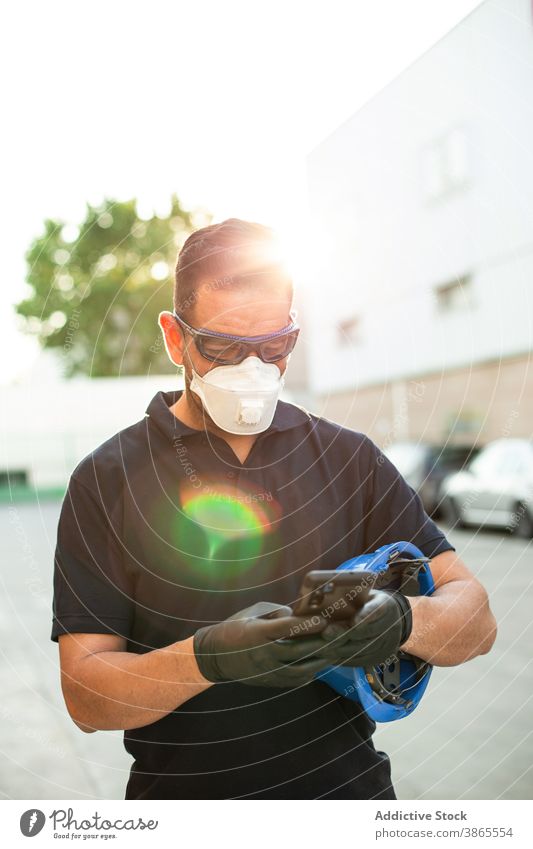 Arbeiter in Schutzmaske mit Smartphone auf der Straße benutzend Mechaniker Atemschutzgerät Handschuh behüten Pause Mann Brille Mobile Telefon Gerät