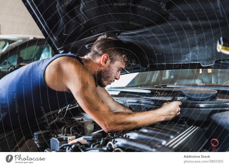 Männlicher Mechaniker schraubt Motor eines Autos ab Mann schrauben PKW Garage Arbeit dreckig Flugzeugwartung Reparatur männlich fixieren Fahrzeug Verkehr Beruf
