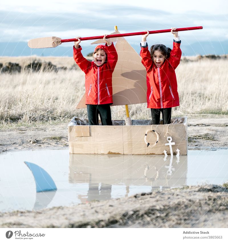 Aufgeregte Mädchen spielen in Karton Boot auf dem Lande Spaß haben Schachtel Kind Zusammensein Inspiration Paddel Spiel kreativ Vorstellungskraft handgefertigt