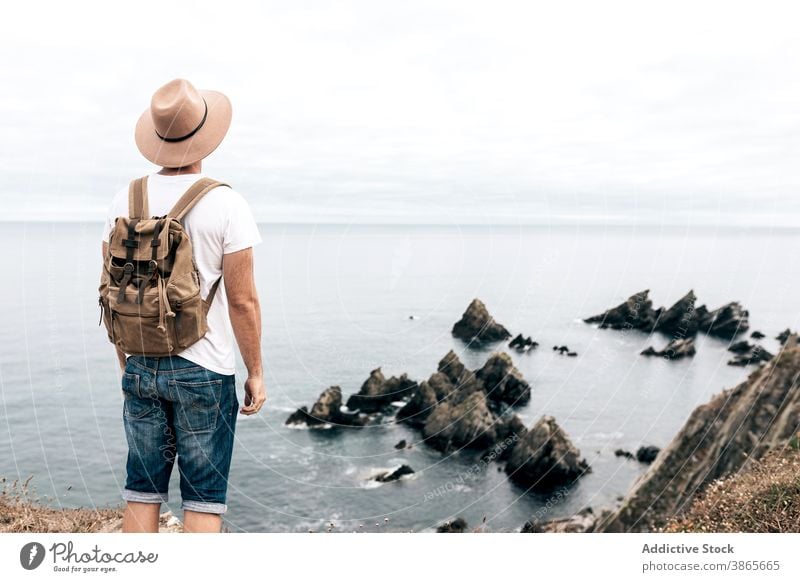 Mann steht auf einem Hügel und genießt die Meereslandschaft Reisender beobachten Aussichtspunkt erkunden Fernweh Abenteuer wunderbar männlich Landschaft felsig