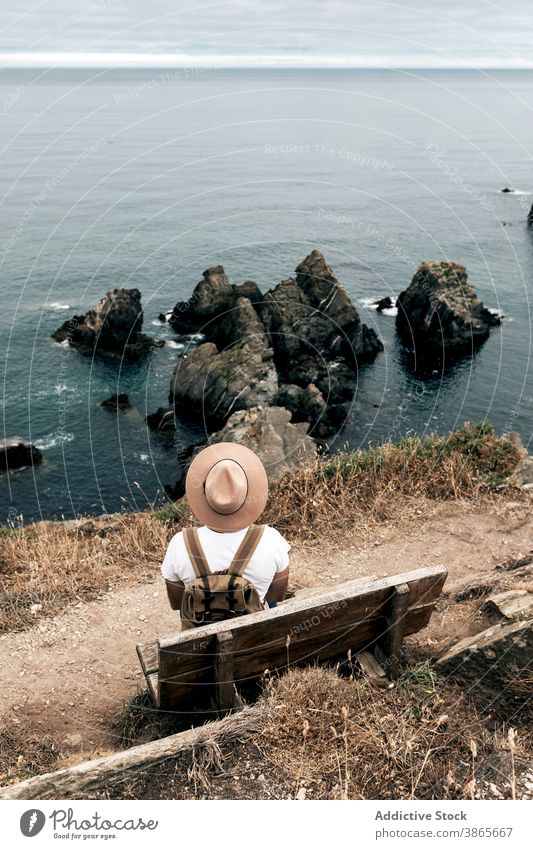 Reisende sitzen auf der Bank und genießen malerische Meereslandschaft reisen Mann Klippe bewundern Landschaft MEER Hügel Reisender erkunden männlich Entdecker