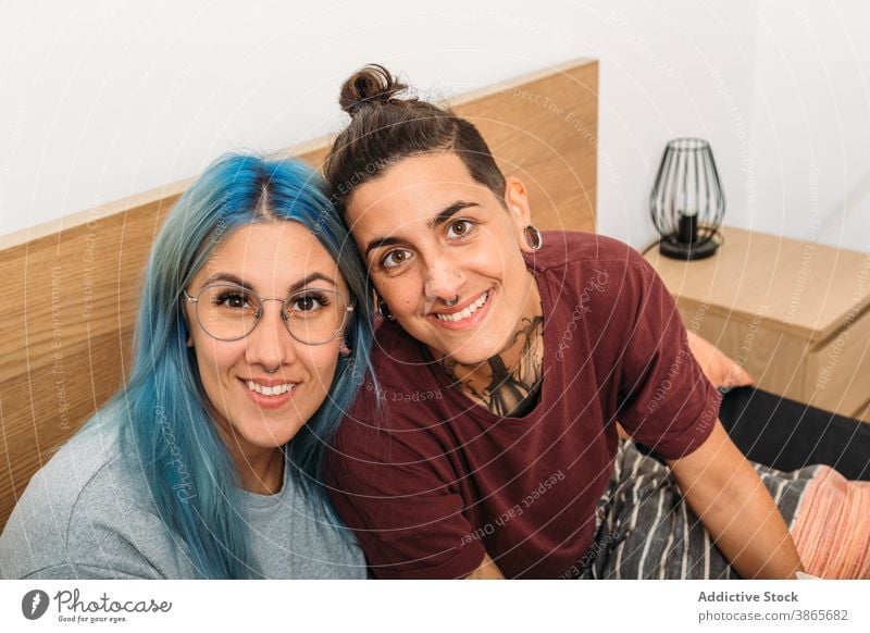 Junges lesbisches Paar sitzt auf dem Bett Frauen Kuss Liebe Glück Angebot Partnerschaft Freundin Lächeln Schlafzimmer heimwärts androgyn Bonden froh
