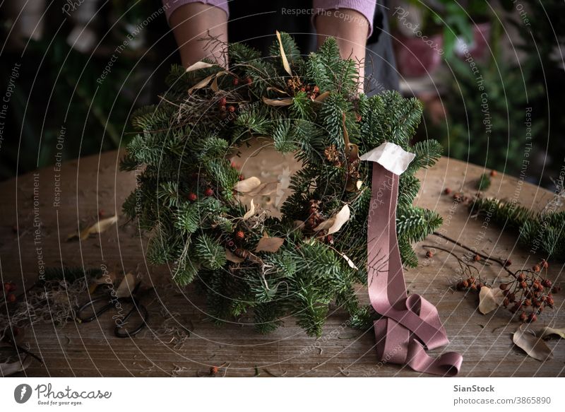 Frau macht Weihnachtskranz aus Fichtenholz, Schritt für Schritt. Konzept der Arbeit des Floristen vor den Weihnachtsfeiertagen. Bändchen Hand Herstellung Hände