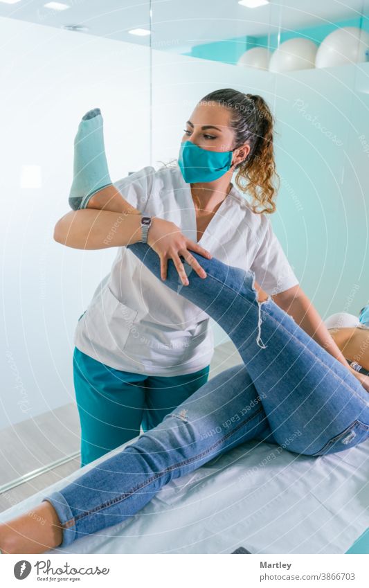 Therapeutin, die das Bein eines Patienten während einer Physiotherapie-Sitzung in einer modernen Klinik streckt Physiotherapeutin Rehabilitation Massage Frau