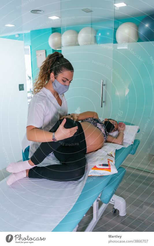 Therapeutin, die das Bein einer Schwangeren während einer Physiotherapie-Sitzung in einer modernen Klinik streckt Schwangerschaft schwanger pränatal