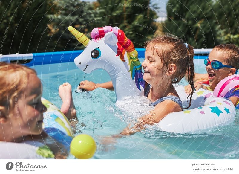 Kinder, die in einem Pool in einem Hausgarten spielen. Kinder, die an einem sonnigen Sommertag Spaß am gemeinsamen Spielen haben authentisch Hinterhof Kindheit