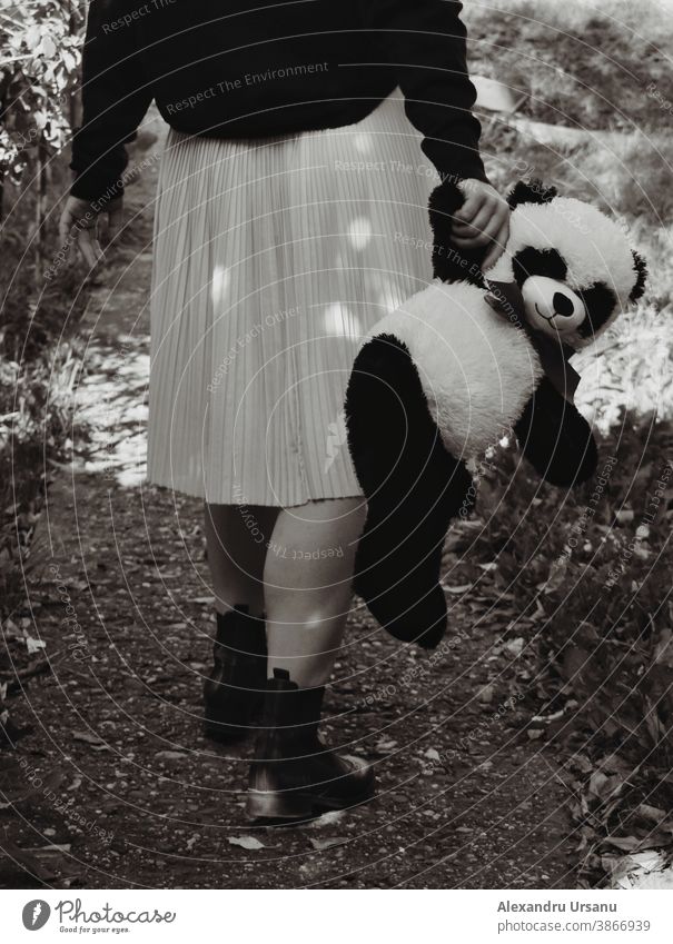 Ein Mädchen geht mit einem Bären in der Hand. Beine laufen Spielzeug Kindheit traurig
