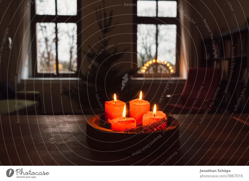 Adventskranz mit brennenden roten Kerzen auf Holztisch stehend im Wohnzimmer mit Kerzenbogen im Fenster hell Christentum Weihnachten Weihnachten & Advent