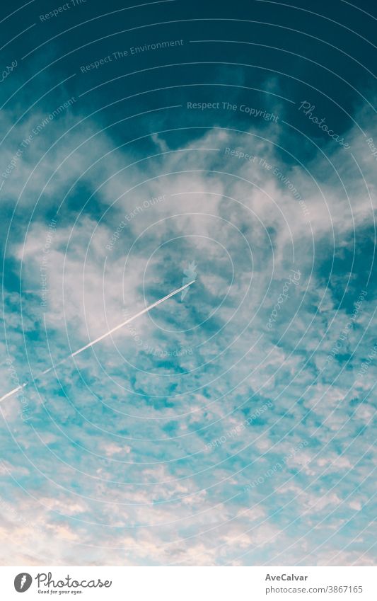 Flugzeug, das am Himmel zwischen den Wolken in einem minimalistischen Bild mit gesättigtem Blau fliegt Ebene Nachlauf Rauch Silhouette fliegen Geschwindigkeit