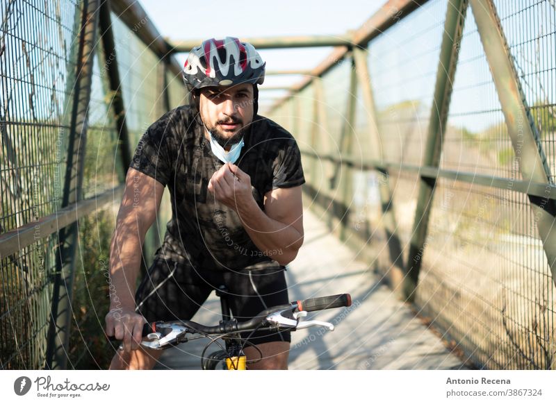 Biker mit Gesichtsmaske trainiert Sport in Pandemiezeiten Männer covid-19 Corona-Virus coronaviorus Mundschutz Fahrrad Schutzhelm im Freien Mann Erwachsener Tag