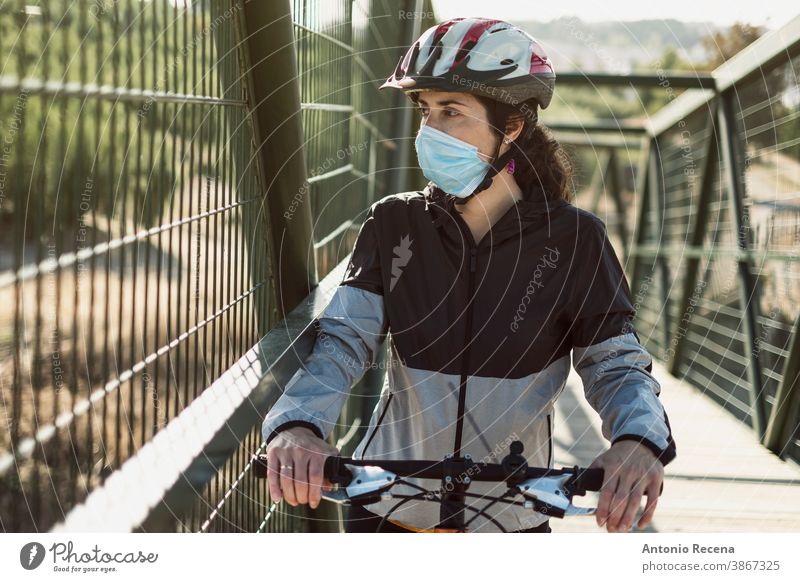 Biker mit Gesichtsmaske trainiert Sport in Pandemiezeiten Frau Frauen covid-19 Corona-Virus coronaviorus Mundschutz Fahrrad Schutzhelm im Freien Tag dylight