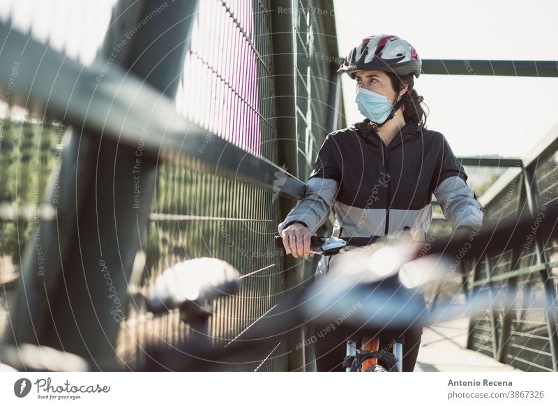 Biker mit Gesichtsmaske trainiert Sport in Pandemiezeiten Frau Frauen covid-19 Corona-Virus coronaviorus Mundschutz Fahrrad Schutzhelm im Freien Tag dylight