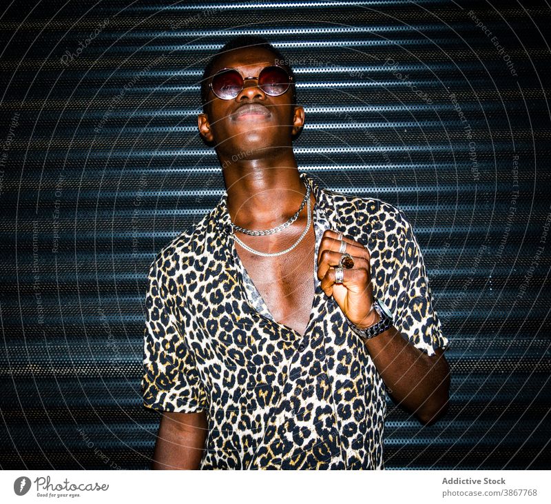 Stilvoller schwarzer Mann in trendigem Outfit in der Stadt Leopard drucken cool Mode urban Großstadt selbstbewusst männlich ethnisch Afroamerikaner Straße Nacht