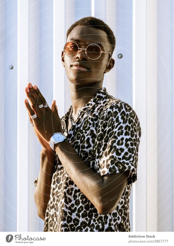 Ethnischer Mann in stilvollem Outfit auf der Straße Stil Leopard Sonnenbrille Großstadt trendy heiter Daumen hoch gestikulieren jung männlich schwarz Shaka