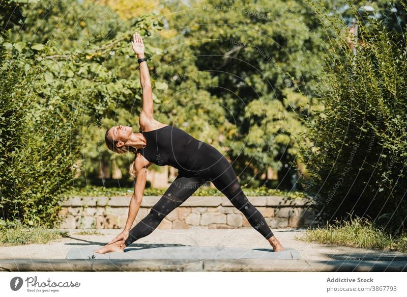 Flexible Frau tun seitliche Biegung Yoga-Pose im Park Dreieck trikonasana Wegbiegung stehen üben positionieren Gleichgewicht Asana beweglich passen Wellness