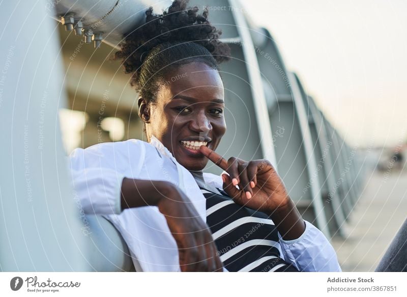 Lächelnde afroamerikanische Frau, die sich auf der Straße ausruht heiter Glück urban jung genießen positiv ruhen Inhalt Afro-Look schwarz Schüler Afroamerikaner