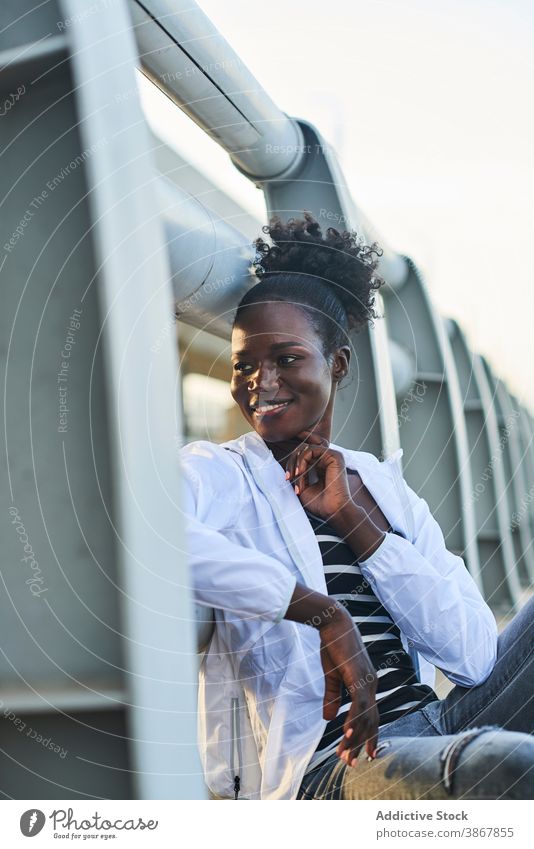 Lächelnde afroamerikanische Frau, die sich auf der Straße ausruht heiter Glück urban jung genießen positiv ruhen Inhalt Afro-Look schwarz Schüler Afroamerikaner