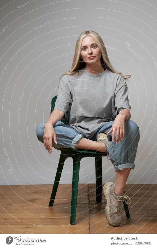 Frau in Streetstyle-Kleidung im Studio cool unabhängig jung trendy Stil Outfit modern selbstbewusst Model Zeitgenosse Individualität Generation sitzen Stuhl