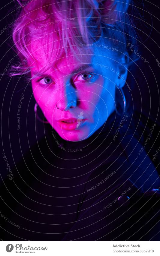 Junge Frau in Neon-Beleuchtung in der Dunkelheit selbstbewusst neonfarbig Menschliches Gesicht Porträt dunkel blond ernst modern Model jung purpur leuchten Stil