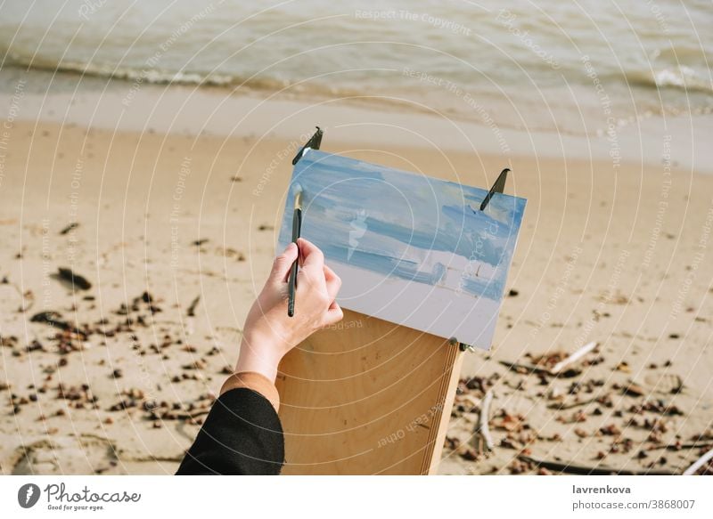 Nahaufnahme einer Pinselzeichnung mit weiblicher Hand am Strand Anstreicher im Freien Person Leinwand Kunst Freizeit Bürste Hobby Künstler kreativ Staffelei