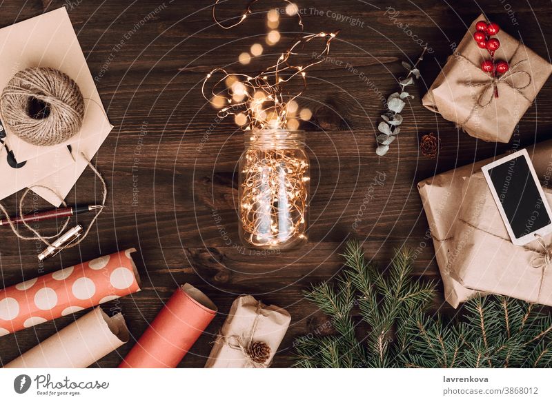 Anordnung von verpackten Geschenken und Glas mit Weihnachtsbeleuchtung auf dunklem Holzuntergrund Bokeh Kasten Ast Postkarte Feier Weihnachten Bastelpapier