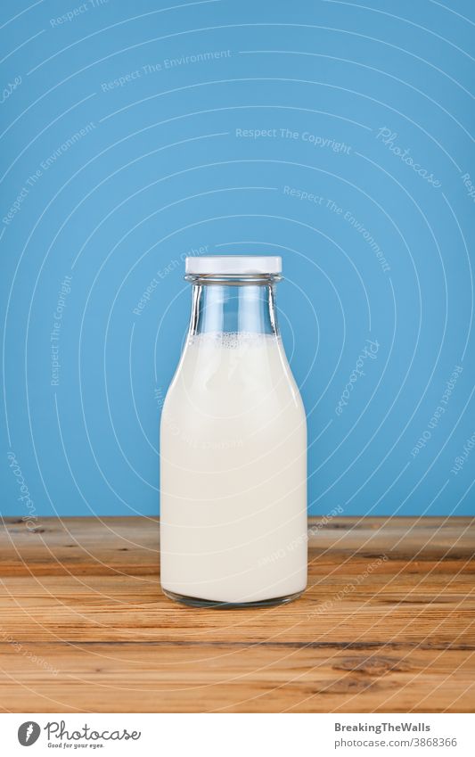 Schließen Sie eine Glasflasche mit Milch über Blau melken Joghurt frisch Flasche satt Nahaufnahme blau Hintergrund Tisch niedriger Winkel Ansicht Seite
