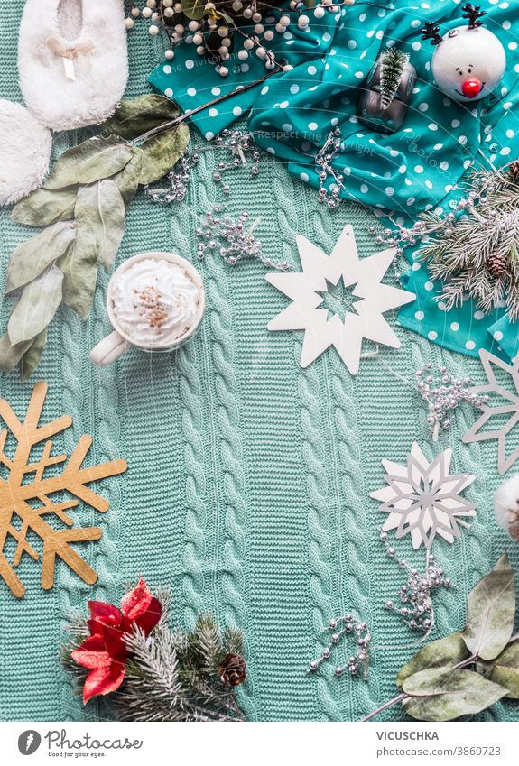 Winterlicher Lifestyle-Hintergrund mit blauer Decke, Tasse Cappuccino und verschiedener Weihnachtsdekoration. Ansicht von oben. Rahmen Wintersport Draufsicht