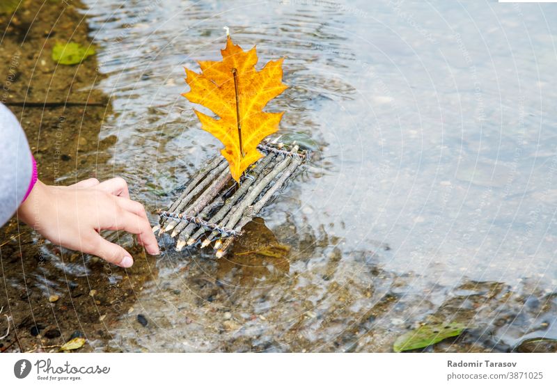 Mädchen, das ein handgefertigtes kleines Spielzeugfloß aus Holz in den Fluss stellt hölzern Floß Segel Wasser einfach Natur Objekt Hintergrund Landschaft