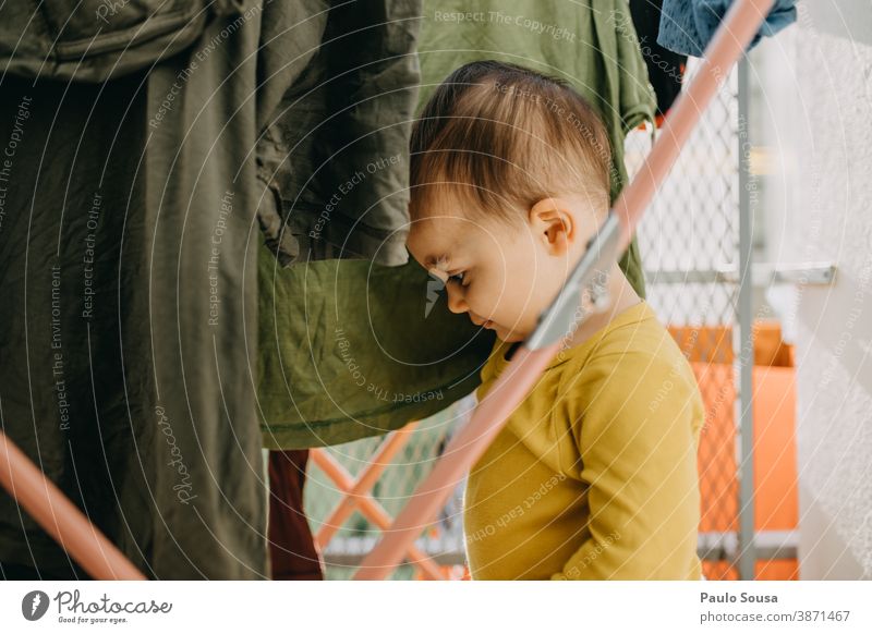 Kleinkind spielt mit Kleidung auf der Wäscheleine 0-09 Jahre Lifestyle anhänglich zu Hause authentisch Herbst fürsorglich lässig Kaukasier Kind Farbe Neugier