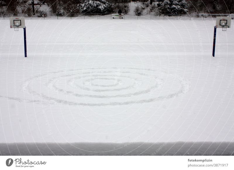 einsame symmetrische Spuren im Schnee auf einem Sportplatz Symmetrie schnee Schneespur spirale basketballfeld Basketball Menschenleer Basketballkorb Ballsport