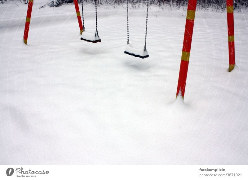 leerer Spielplatz mit zwei Schaukel im Schnee zugeschneit verschneit Winter weiß schnee Wintersport Kinderbetreuung Schneedecke spuren im schnee einsam