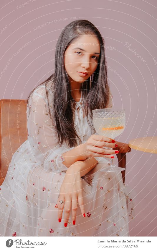Junge Frau mit einem Glas Cocktail in der Hand. Studiofoto mit rosa Hintergrund. Alkohol attraktiv schön Schönheit Getränk trinken elegant Mode Gin Tonic