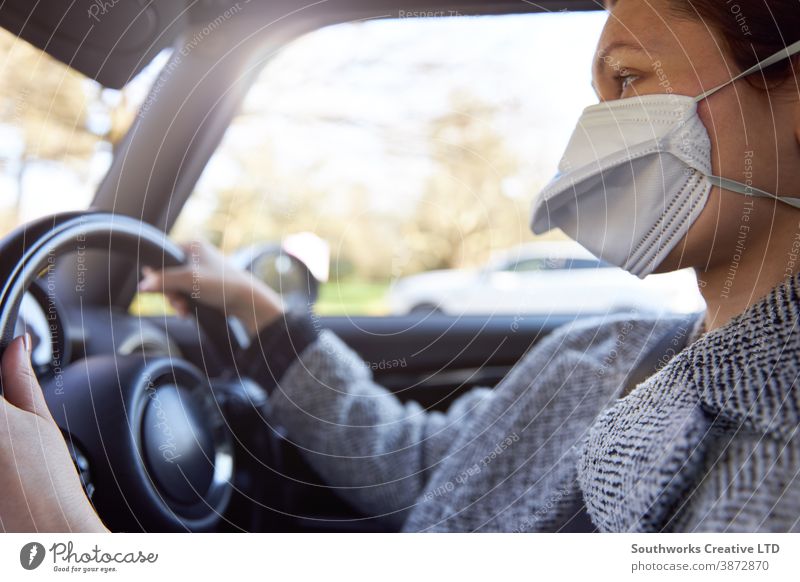 Junge Frau mit Schutzmaske beim Autofahren Mundschutz Kaukasier PKW schützend jung tragend lenken Fahrzeug horizontal Gesicht Person Erwachsener Laufwerk