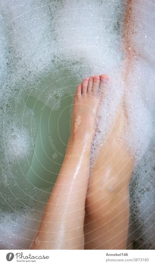 Frauenbeine in der Badewanne, Baden mit Sprudelbadschaum von oben, Entspannungs-Schönheitsspa-Konzept Pflege Hygiene Seife schäumen Körper jung Erholung Wasser