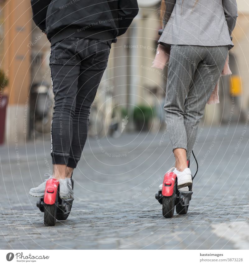 Rückansicht nicht wiederzuerkennender, trendiger, faschinierbarer Teenager auf öffentlichen Leih-Elektrorollern in städtischer Umgebung. Neuer umweltfreundlicher, moderner öffentlicher Stadtverkehr in Ljubljana, Slowenien.