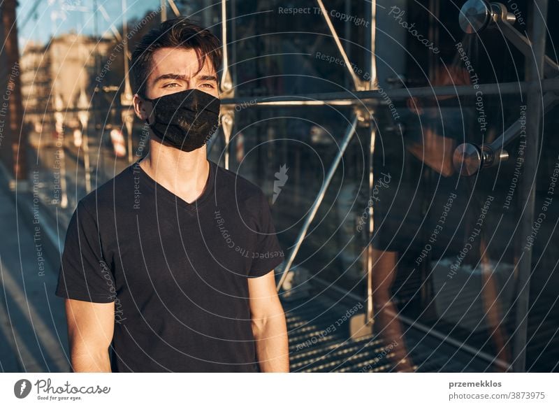 Junger Mann geht im Stadtzentrum entlang der Glasfront eines Geschäfts und trägt die Gesichtsmaske, um eine Virusinfektion zu vermeiden Pflege Kaukasier Zentrum