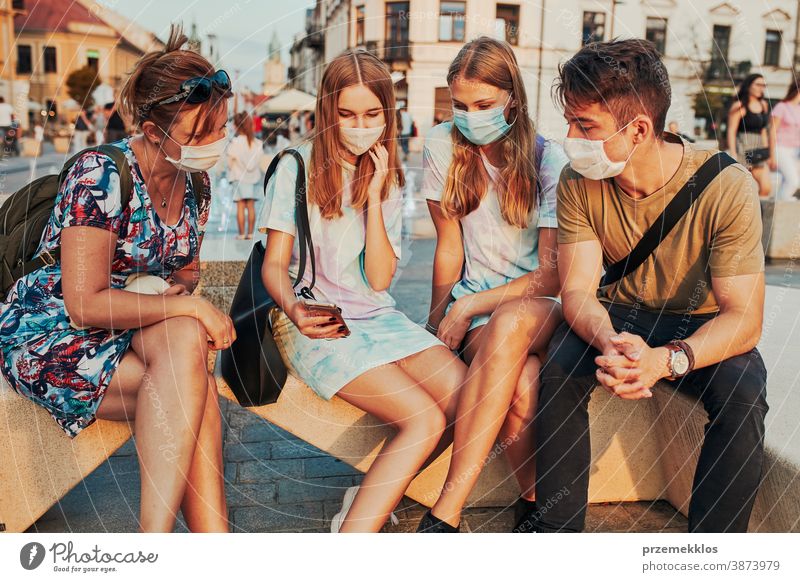 Junge Frauen verbringen Zeit miteinander, indem sie im Stadtzentrum sitzen und die Gesichtsmasken tragen, um eine Virusinfektion zu vermeiden Kaukasier Gespräch